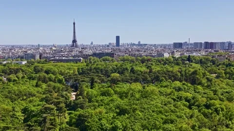Drone flying over lush green forest of Bois de Boulogne with Paris cityscape Stock Footage 336251073