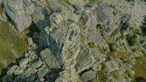 Drone flying over mountain peak with bare rocks surrounded by vegetation Stock Footage 137591863