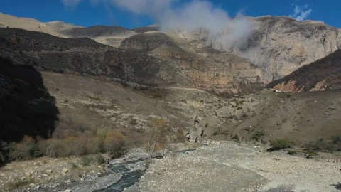Drone Flying Over Mountain Stream Towards Rocky Peaks 動画素材 318883692