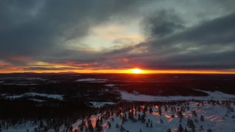Drone flying over mountain top revealing winter sunset over forest in Lapland Stock Footage 301343098