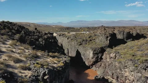 Drone flying over a muddy river that flows through the desert, carving a canyon Stock Footage 255862203