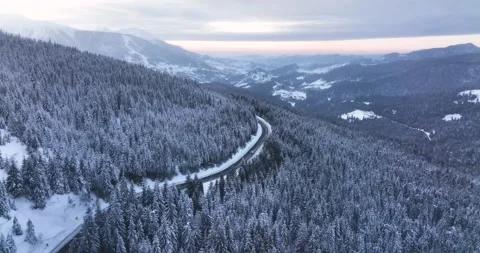 Drone flying over narrow winding road. Middle of the snow-covered white mountain Video stock 205096599