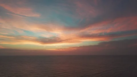 Drone Flying Over Ocean Under Vibrant Orange and Blue Sky Stock Footage 343420254