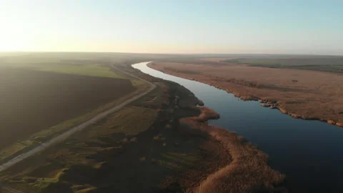 Drone flying over the river with dry reeds on the bank. There are fields Stock Footage 158691261