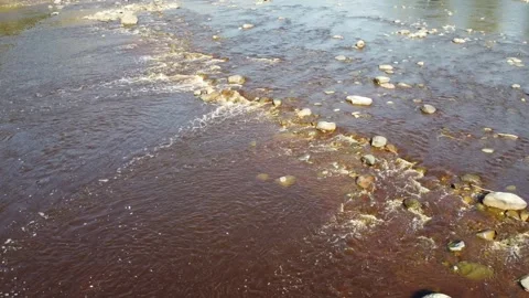 Drone flying over river with lots of rocks with brown water on a sunny day Stock Footage 279942638