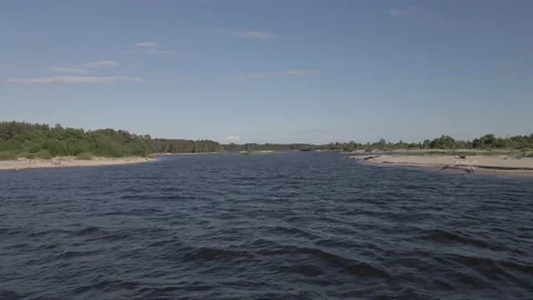 Drone flying over a river with sandy shoreline and forest in the background Stock Footage 161153690