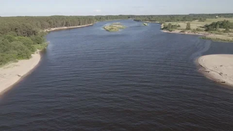 Drone flying over a river with sandy shoreline and forest in the background Stock Footage 161153695