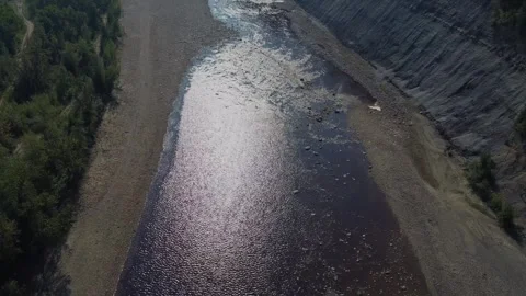 Drone flying over river on sunny day with beach and steep hill Stock Footage 279900251