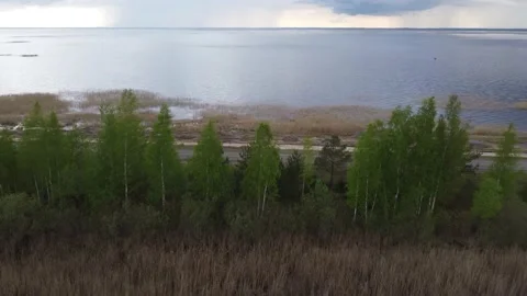 Drone flying over a road to a huge lake with dramatic clouds in background Stock-Footage 154825602