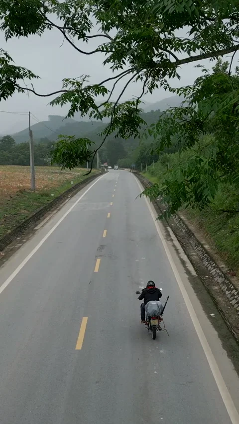 Drone flying over a road with a motorcycle that doesn't work very well in Stock Footage 293612948