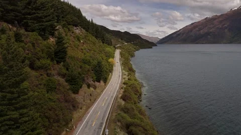 Drone flying over the road next to the mountains and shores of Lake Wakatipu on Stock Footage 330852116