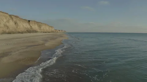 A drone flying over a sandy seashore on a cloudy Stock Footage 241315906
