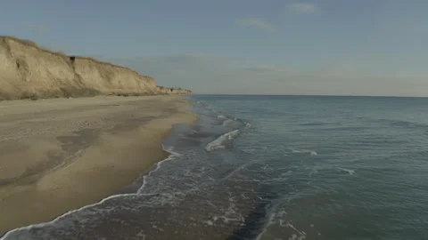 A drone flying over a sandy seashore on a cloudy Stock Footage 241316404