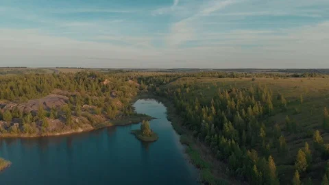 Drone flying over small lake surrounded by sparse vegetation with blue skies and Stock Footage 120009566