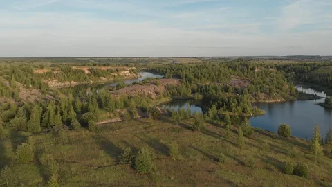 Drone flying over small lake surrounded by sparse vegetation with blue skies and Stock Footage 120117202