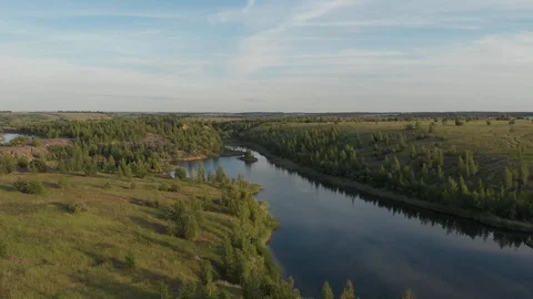 Drone flying over small lake surrounded by sparse vegetation with blue skies and Stock Footage 120117372