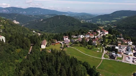 Drone Flying Over Small Mountain Village Surrounded by Alpine Ranges Stock Footage 323607676