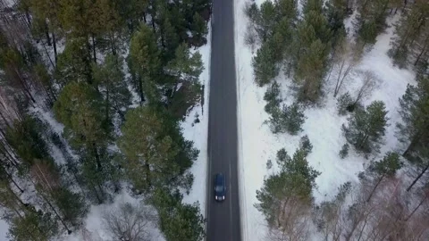 Drone flying over a snowy forest and a car passes by. Stock Footage 143615416