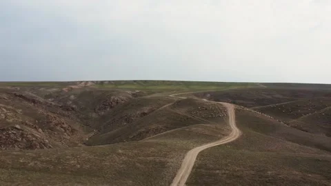 Drone flying over spring steppe with dirt road, hills and Reservoir in KZ Stock Footage 332984902