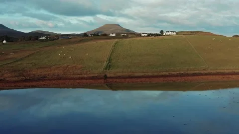 Drone flying over still calm reflective lake during sunrise in Isle of Skye Stock Footage 167732803