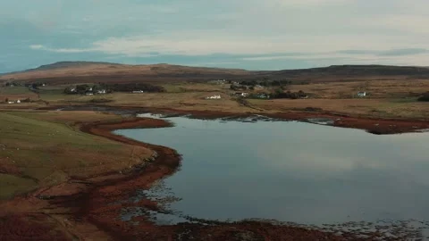 Drone flying over still calm reflective lake during sunrise in Isle of Skye Stock Footage 167732919