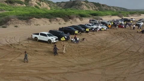 Drone flying over SUV jeep vehicle rally parking in sand near the beach Stock Footage 256219352