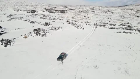 Drone flying over an SUV moving through snow-covered mountains 스톡 동영상 280379423