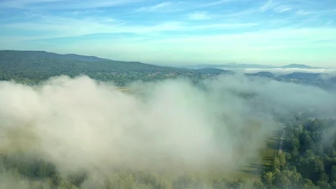 Drone flying over the terrain with fields and mountain range in a small fog Stock Footage 114978386