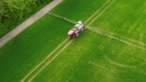 Drone flying over a tractor fertilizing a green field 4K Stock Footage 273863345