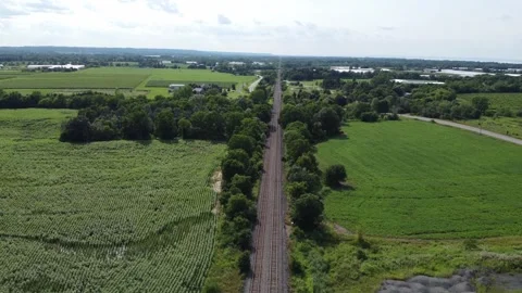 Drone flying over train tracks on sunny day tilts up showing countryside 스톡 동영상 280009397