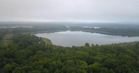 Drone flying over trees towards large lake Stock Footage 114368434