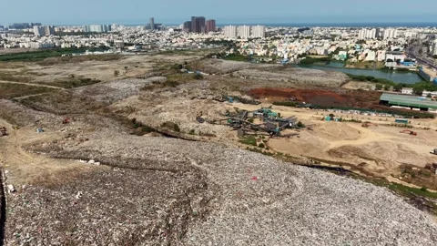 Drone Flying Over A Waste Dump Yard And City Buildings Near The Beach Stock Footage 341465977