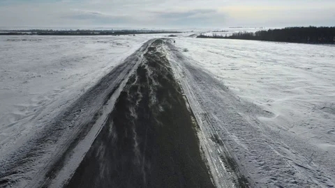 Drone flying over the winter road. Wind overtakes the snow across the road. Cold Video stock 102537929