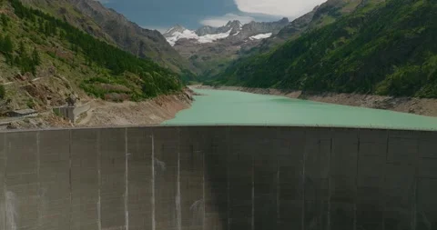 Drone Flying Parallel to High Dam Wall with Turquoise Water Reservoir and Stock Footage 342345475