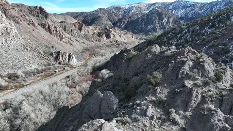Drone flying past mountain peak revealing highway through the canyon Stock Footage 229807432