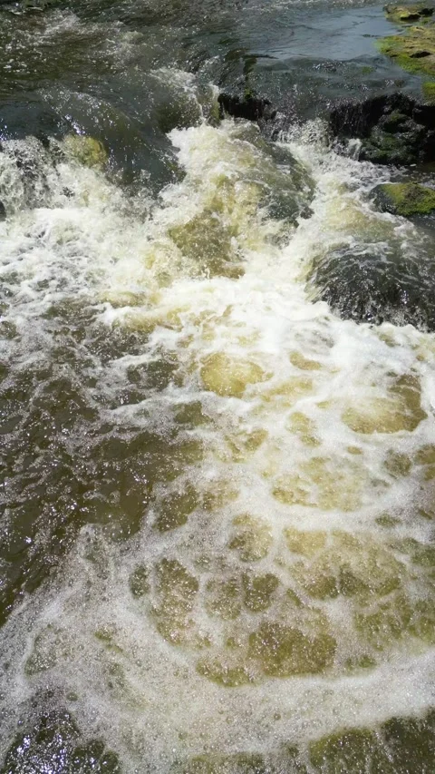 Drone flying up river over a small waterfall slowly tilting up Video stock 246717535