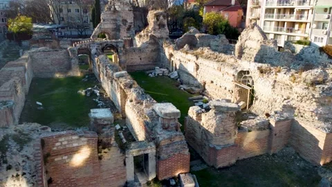 Drone flying sideways over old Roman Thermae ruin with green grass in Stock Footage 226292874