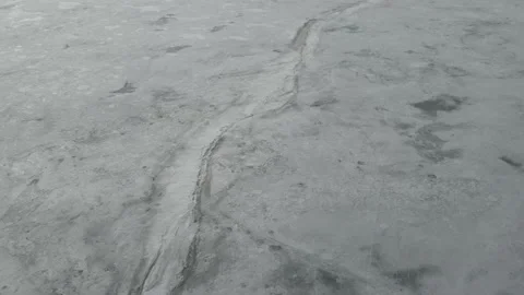Drone flying slowly forward and looking down at a frozen lake that has cracks Stock Footage 151906097