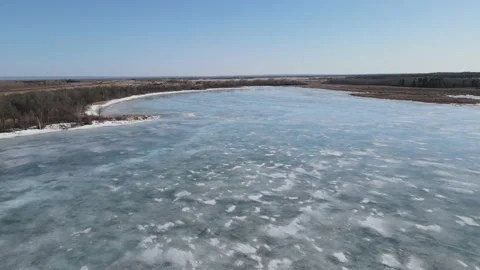 Drone flying slowly forward over a frozen lake with the blue sky reflecting  Stock Footage 151707212