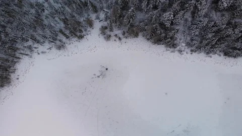 Drone flying slowly high above a winter scene with snow covered pond and forest Stock Footage 120744136