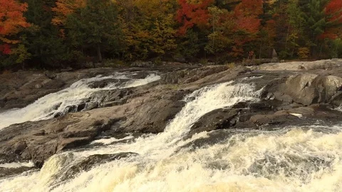 Drone flying slowly right over waterfalls towards autumn forest Video stock 119189343