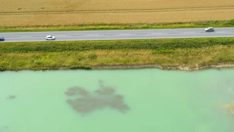 Drone flying slowly sideways over a road with a corn field and a small lake.. Stock Footage 305564451