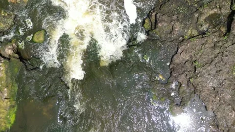 Drone flying straight up over a small waterfall Video stock 246717627