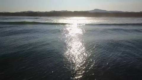 Drone flying into sun as two SUP Surfers paddle out at Playa Avellana Stock Footage 90913736