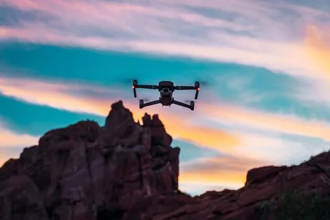 Drone flying at sunset, with mountainous background Stock Photos