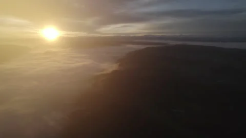 Drone flying through clouds over forest at sunrise, cinematic alpine landscape Stock Footage 325021482