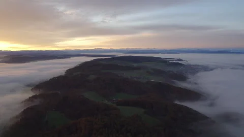 Drone flying through clouds over forest at sunrise, cinematic alpine landscape Stock Footage 325022132