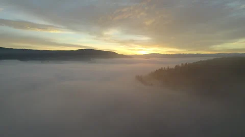 Drone flying through clouds over forest at sunrise, cinematic alpine landscape Stock Footage 325022578