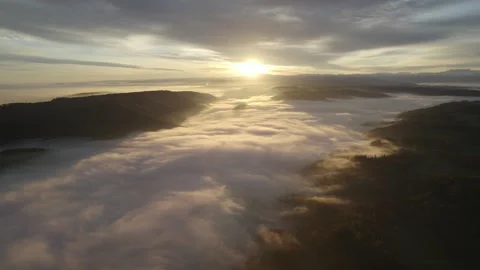 Drone flying through clouds over forest at sunrise, cinematic alpine landscape Stock Footage 325023501