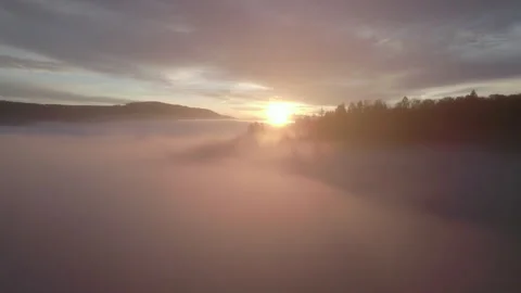 Drone flying through clouds over forest at sunrise, cinematic alpine landscape Stock Footage 325023699